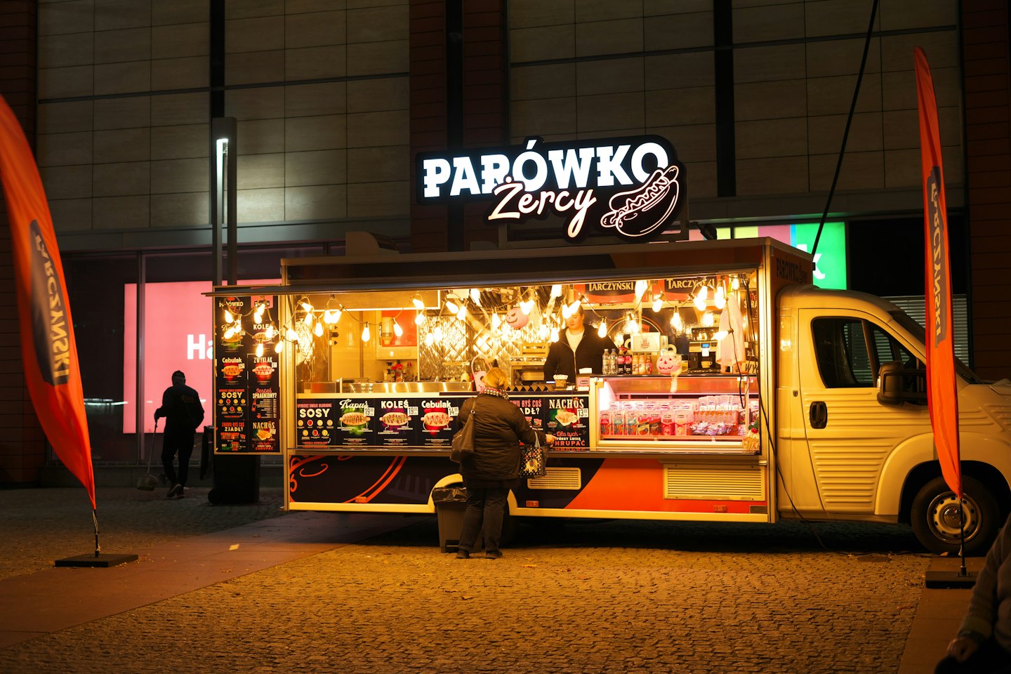 Un cliente ordina cibo da un food truck urbano ben illuminato.