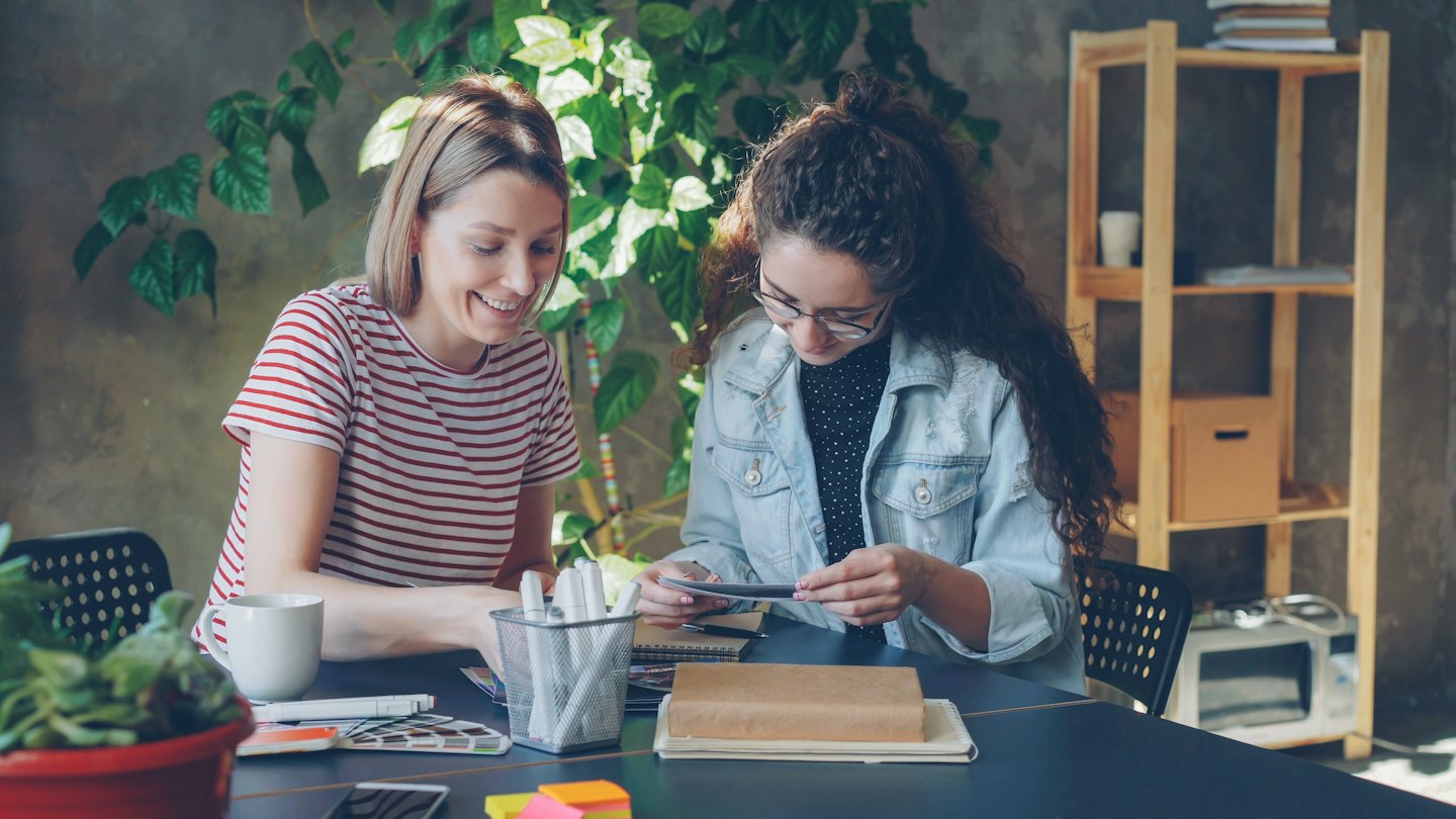Due donne che discutono di materiali di design a un tavolo.