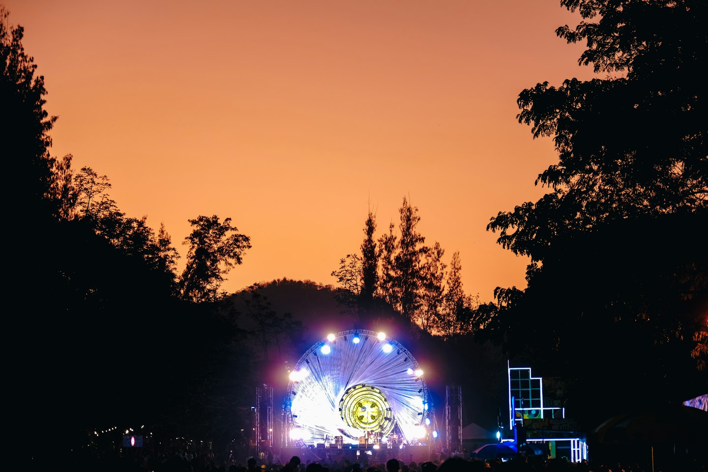 Folla in piedi davanti a un palco illuminato al tramonto.