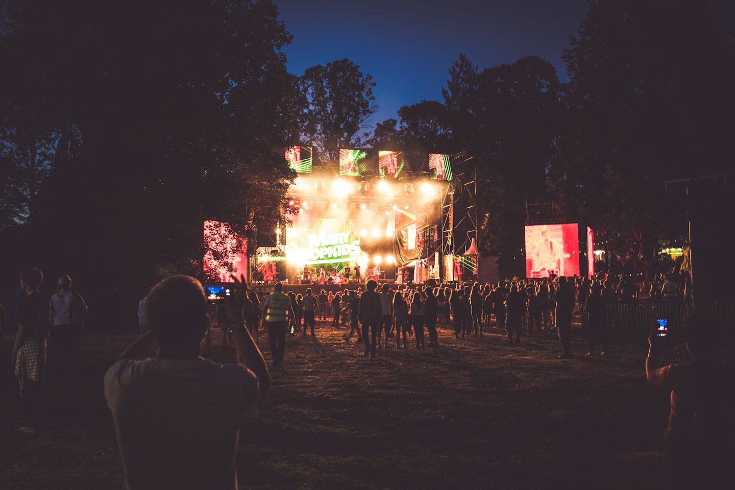 Folla in silhouette si gode una band che suona su un palco illuminato al tramonto.